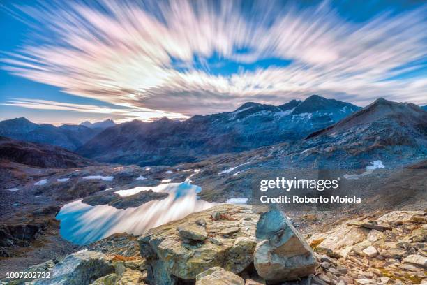 clouds at dawn are reflected in lai ghiacciato framed by peaks, val ursaregls, chiavenna valley, valtellina, lombardy, italy, europe - ghiacciato fotografías e imágenes de stock