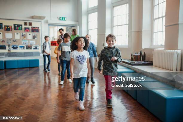 school children walking through the hall with their teachers - school auditorium stock pictures, royalty-free photos & images