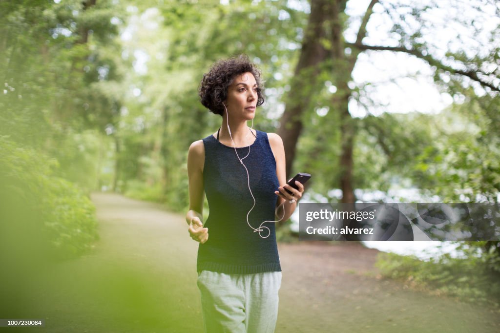Mulher ouvir música enquanto caminhava na floresta