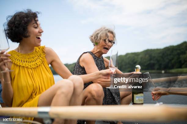 friends with champagne bottle and flutes on boat - senior women wine stock pictures, royalty-free photos & images