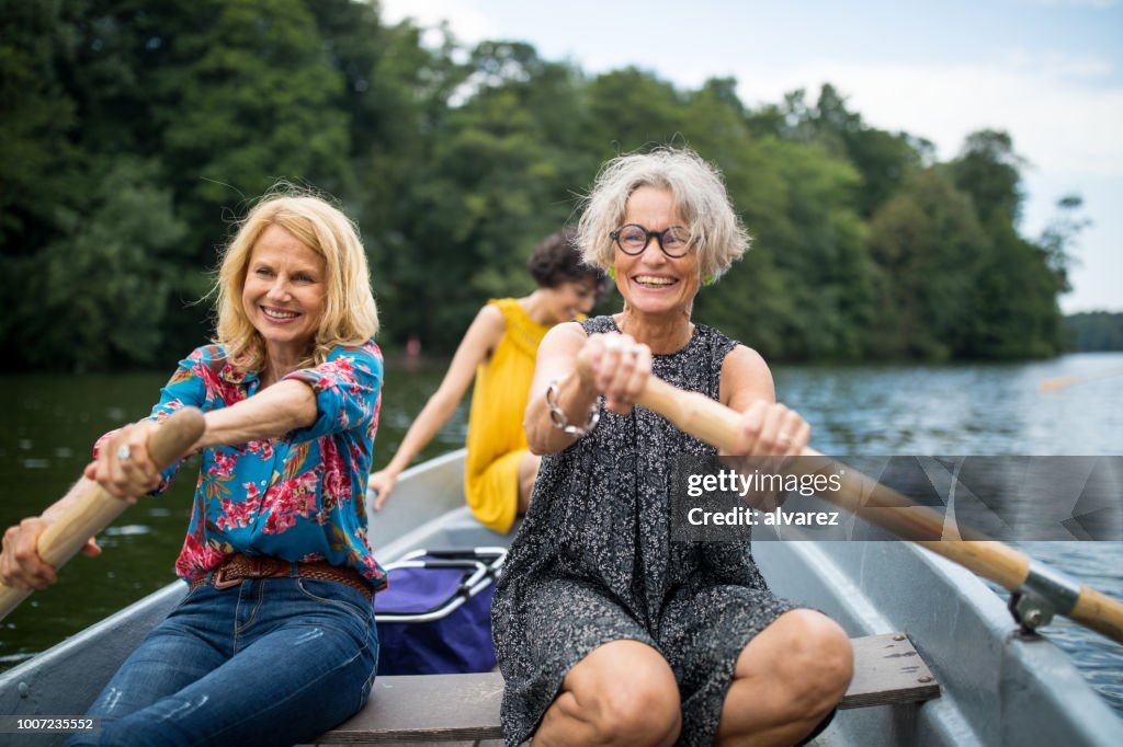 Lächelnden Freundinnen Ruderboot im See