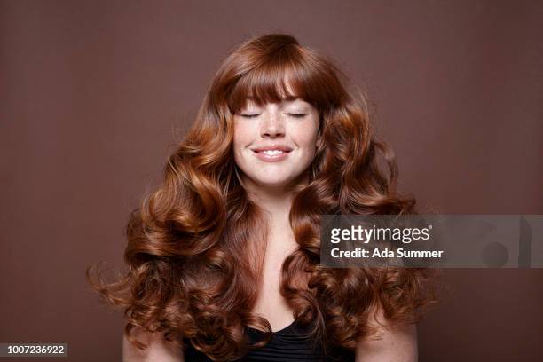 smiling woman with windblown red long hair - hairstyle stock-fotos und bilder