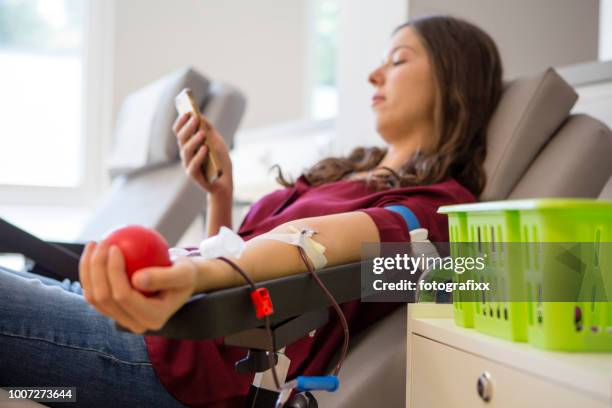junge frau lag auf zurück, während sie blut spenden ist - blutspende stock-fotos und bilder