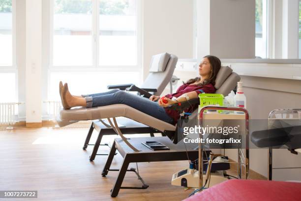 young woman lay on back while she is donating blood - blood bag stock pictures, royalty-free photos & images