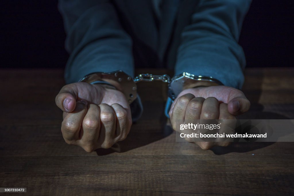 Arrested business man handcuffed hands. Close-up.