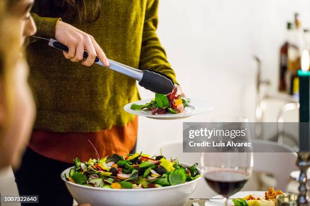woman serving salad while standing during party - pinça utensílio de servir - fotografias e filmes do acervo