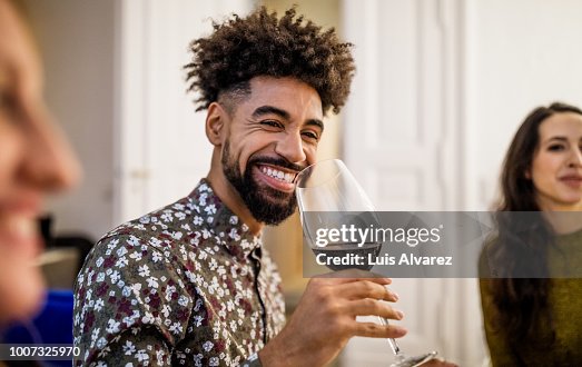Smiling man drinking red wine during dinner party at home Smiling man drinking red wine during dinner party at home