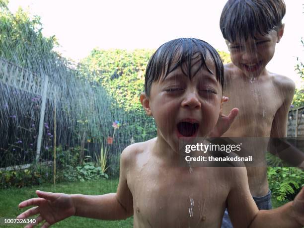 Two boys laughing as they play in water in the backyard