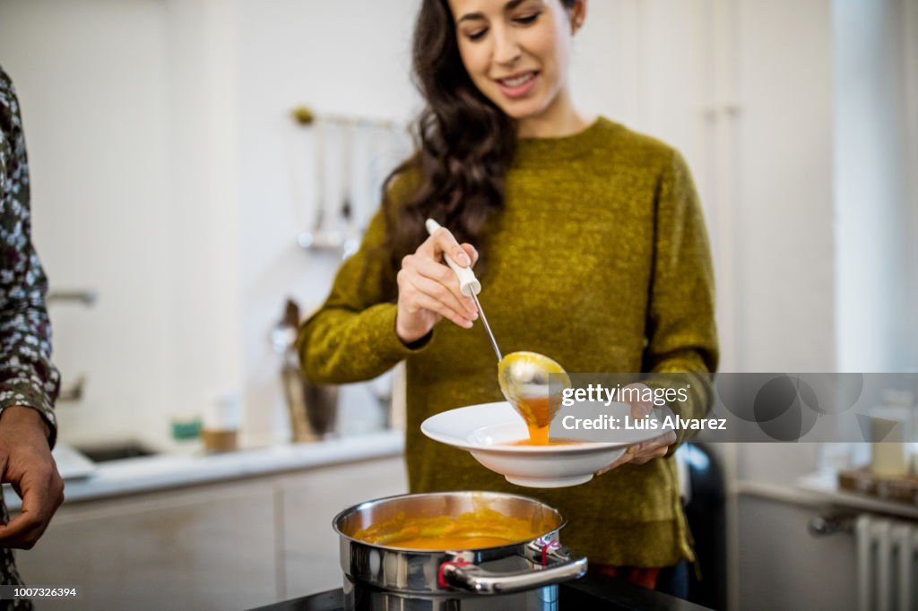 Woman serving squash soup in bowl during dinner party