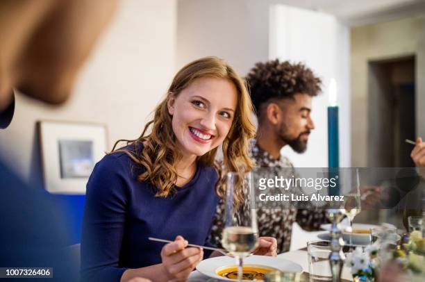 beautiful woman having food with friends at dining table - dinner party menschen raum elegant stock-fotos und bilder