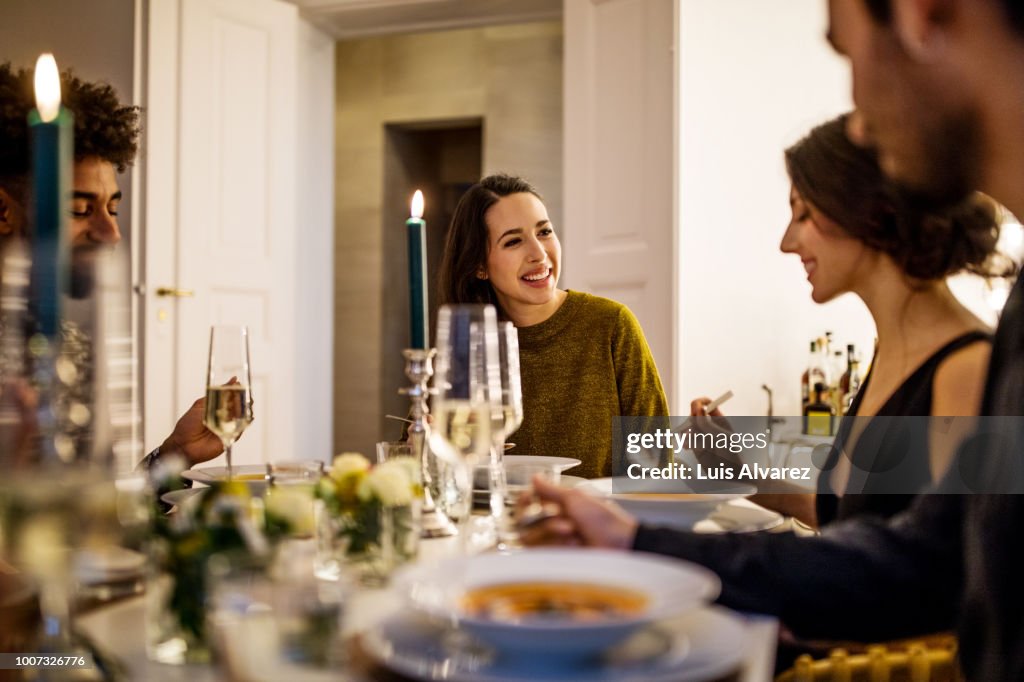 Smiling woman talking with friends while having dinner