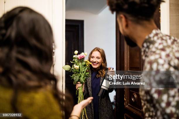 woman holding bouquet and wine bottle while visiting friends - visit stock pictures, royalty-free photos & images