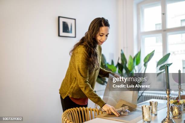 woman arranging dining table for dinner party - arranjo imagens e fotografias de stock