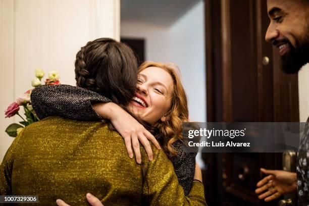 woman embracing friend during visit for dinner party - woman dinner party stock pictures, royalty-free photos & images