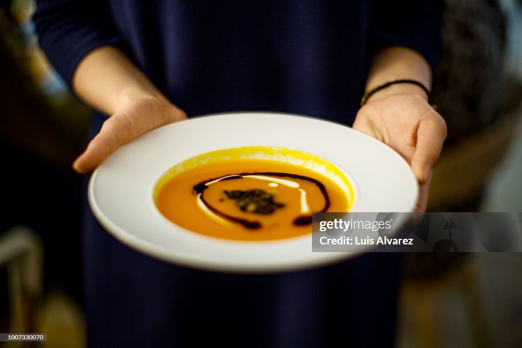 Woman holding squash soup during dinner party