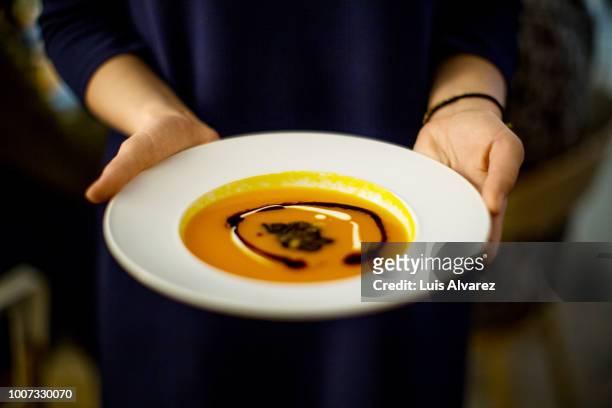 woman holding squash soup during dinner party - pumpkin soup stock pictures, royalty-free photos & images