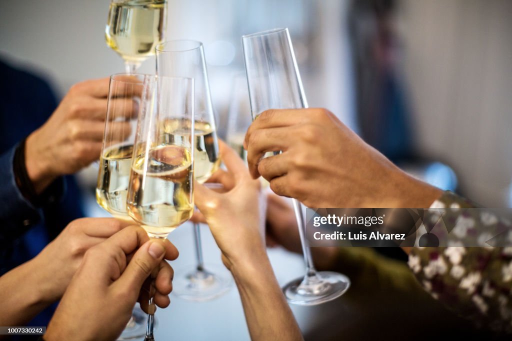 Hands toasting champagne flutes during dinner party
