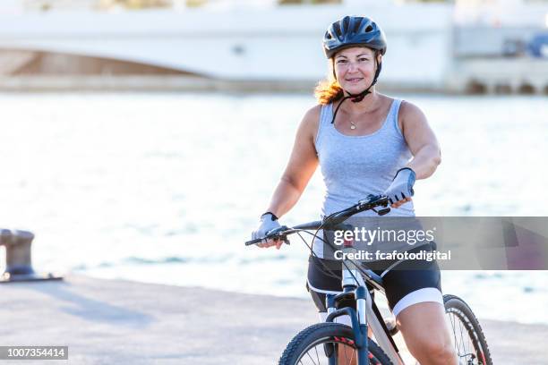 mature woman cycling near sea water on pier in marina - mature woman in water stock pictures, royalty-free photos & images