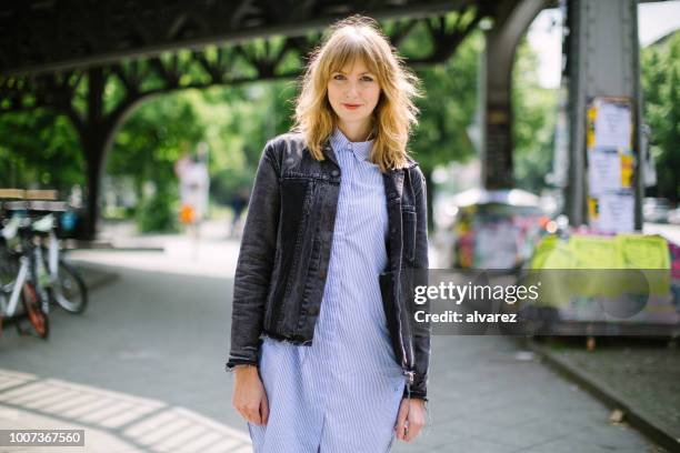 belle jeune femme marchant le long de la rue de la ville - young blonde woman facing away photos et images de collection