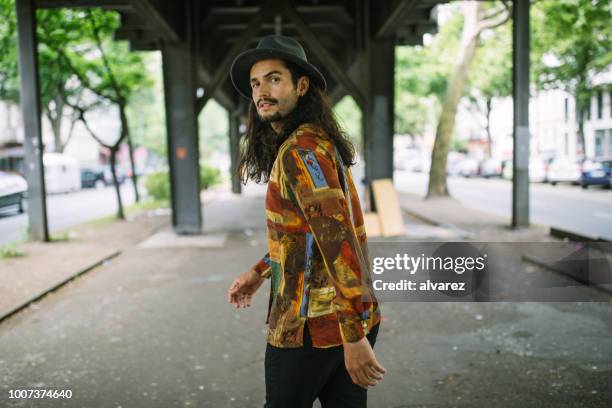 young man walking under the bridge in city - men long hair stock pictures, royalty-free photos & images