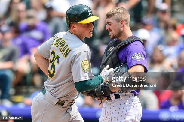 Matt Chapman of the Oakland Athletics touches home plate as Tom Murphy of the Colorado Rockies reacts after Chapman hit a fourth inning solo homerun...