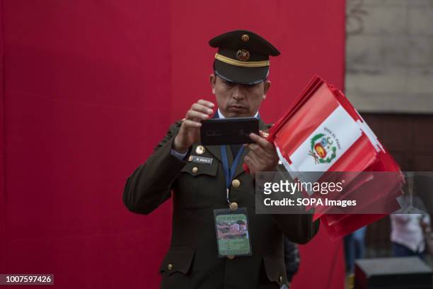 Police officer seen taking pictures with his mobile phone. Members of Peru's armed forces, coastguard, search & rescue, and police march in full...