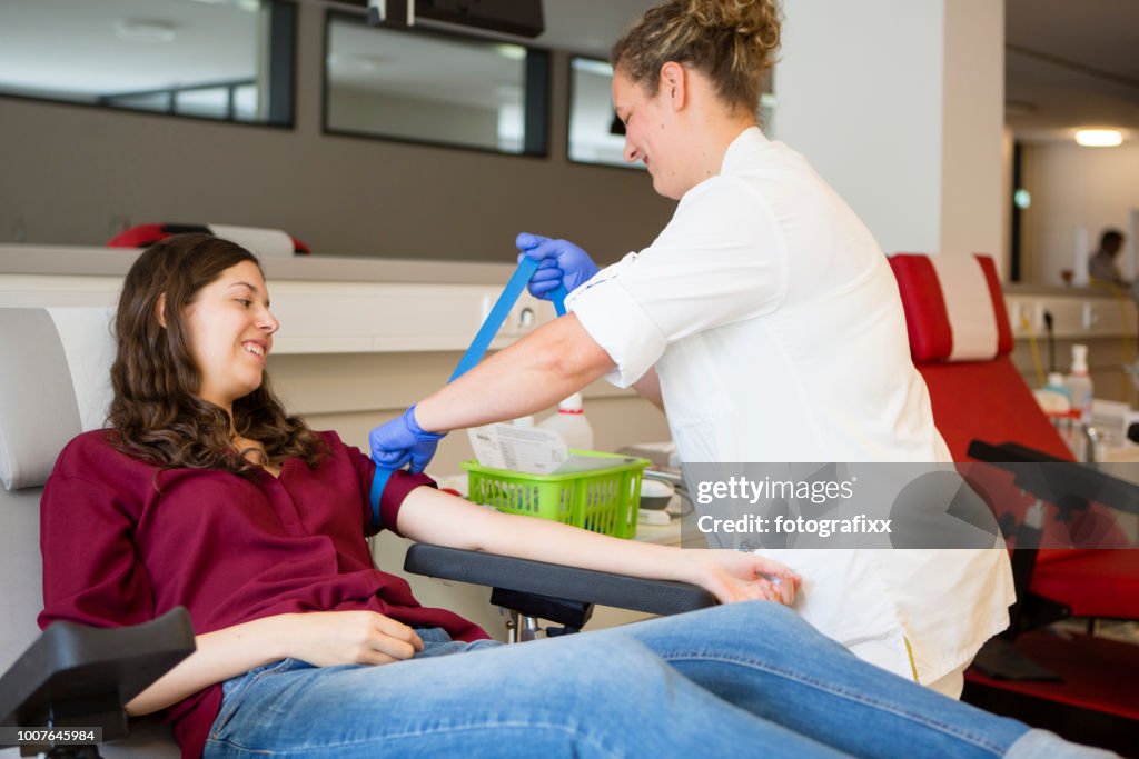 Mujer joven se preparan por una enfermera para la donación de sangre
