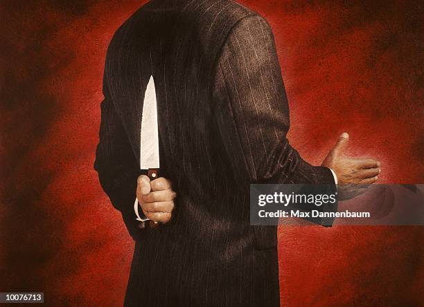 businessman with knife behind back - betrayal photos et images de collection
