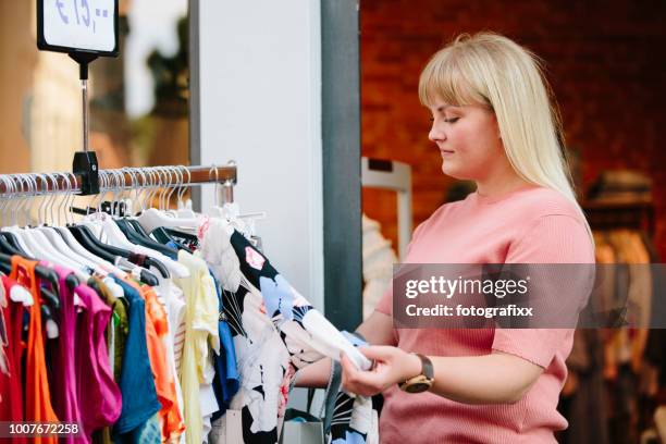 einkaufen: junge frau sucht kleider bei kleiderstange - chubby man shopping stock-fotos und bilder