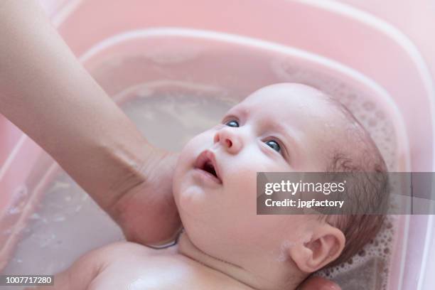 bebé en el baño - bañando bebe fotografías e imágenes de stock