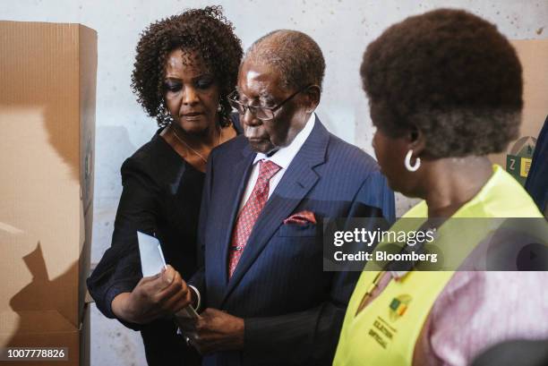 Robert Mugabe, former president of Zimbabwe, exits a voting booth, alongside his wife Grace Mugabe, at a polling station in Highfield, Harare,...