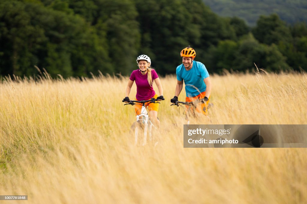 Couple biking through dry grass