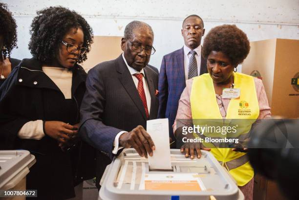 Robert Mugabe, former president of Zimbabwe, center, casts his vote in the ballot box, alongside his daughter Bona Mugabe, left, at a polling station...