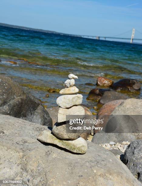 stacked rocks with the mackinac bridge in the distance - pont mackinac photos et images de collection