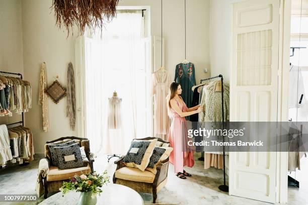 woman looking at dresses while shopping in boutique - clothing boutique stock pictures, royalty-free photos & images