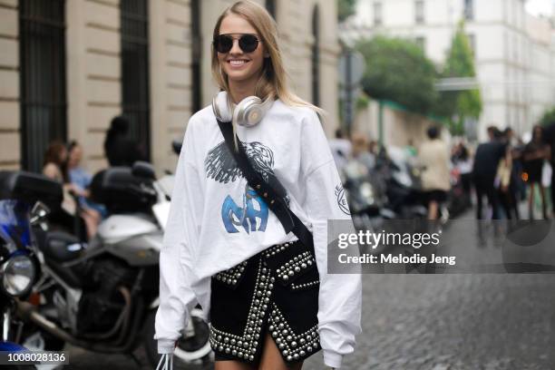 Model Sasha Luss wears black sunglasses, white Beats headphones, and a black asymmetrical studded skirt after the Balmain show during Paris Fashion...