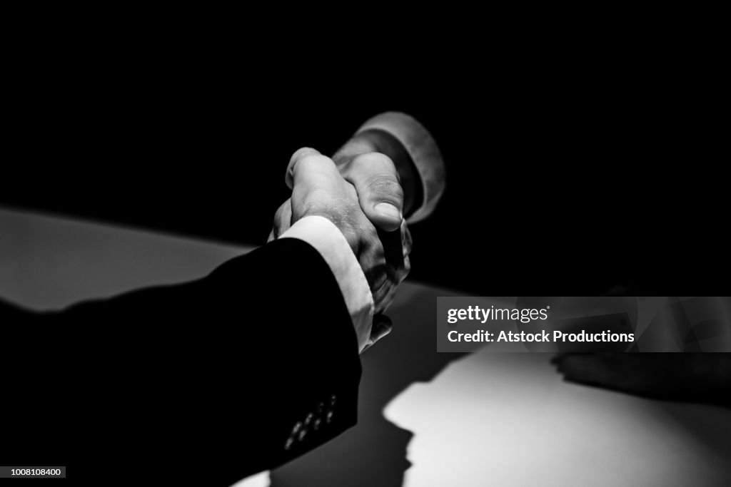 Anonymous business partners making handshake in shadow