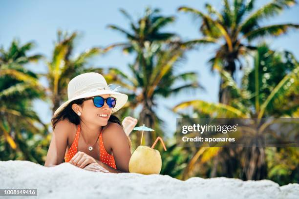 hispanic young woman refreshing with a coconut drink in a tropical white sand island beach in the caribbean sea - coconut beach woman stock pictures, royalty-free photos & images