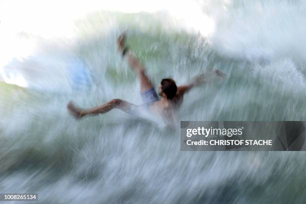 Surfer falls while riding on an artificial wave at the canal of the Eisbach river at the English Garden park in Munich, southern Germany, where...