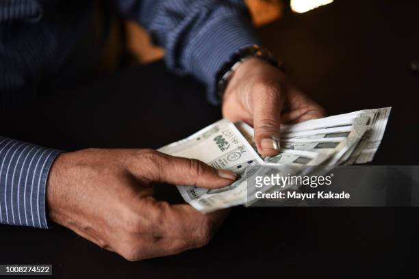 closeup of a hands of a man holding indian rupee currency notes - valuta indiana foto e immagini stock