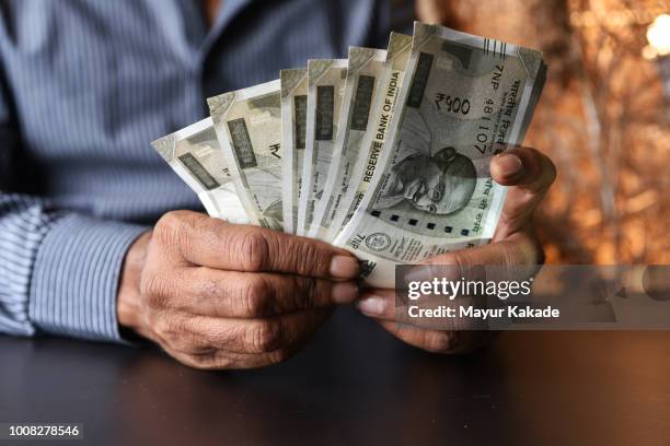 closeup of a hands of a man holding indian rupee currency notes - tax man stock pictures, royalty-free photos & images