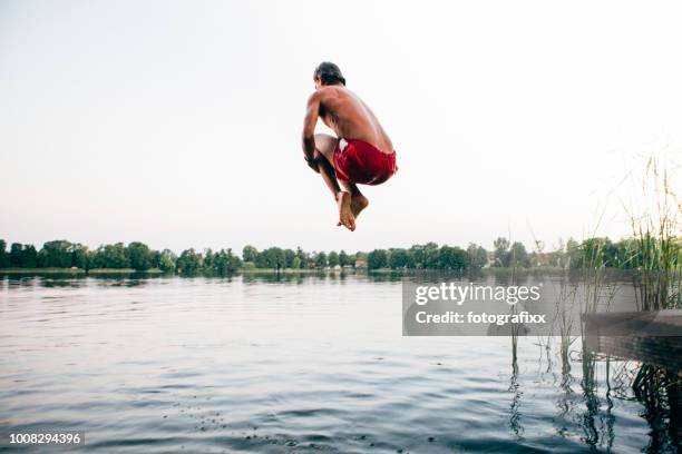 cannonball: young man jumps into a lake - standing water stock pictures, royalty-free photos & images