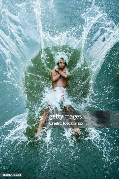 young man jumps backwards into a lake, water splashes around - leaning back stock pictures, royalty-free photos & images