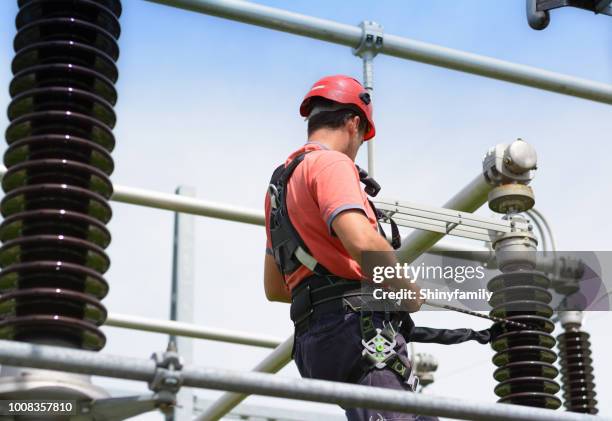 electrician with protective workwear, hardhat and safety harness at work - power line repair stock pictures, royalty-free photos & images