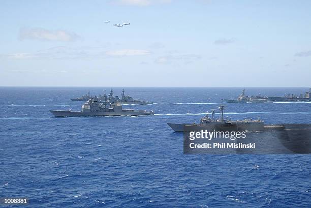 Naval ships from multiple nations steam in formation while a squadron of P-3 ASW aircraft flies over during the RIMPAC excercise operations July 11,...