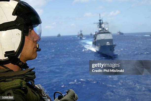 Helicopter crew chief Randall Elkins observes naval ships from multiple nations steam in formation during the RIMPAC excercise operations July 11,...