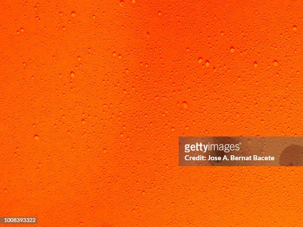 full frame of the textures formed by the bubbles and drops of water, on a smooth orange background. - fond orange photos et images de collection