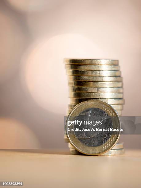 euro  coins arranged in heaps of different sizes, on a table illuminated by the light of the sun. - 1 euro stock-fotos und bilder