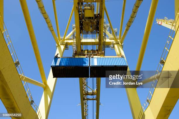 shore crane loading containers in freight ship - grue photos et images de collection