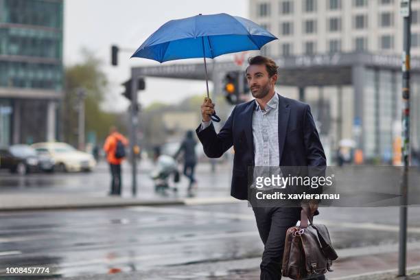 affärsman som innehar paraply medan promenader i city - umbrella bildbanksfoton och bilder